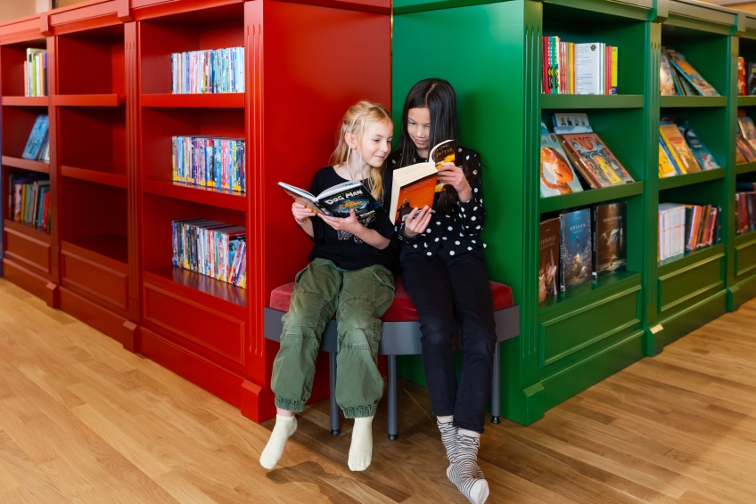 Två barn läser böcker i bibliotek Rum för Barn. 