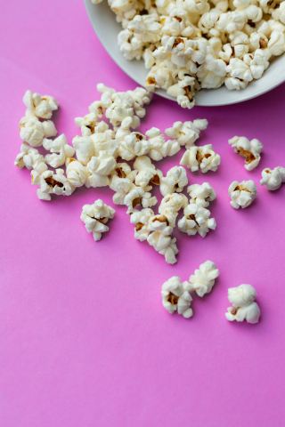 Foto: Yulia Khlebnikova Popcorn ligger utspritt på ett rosa bord.