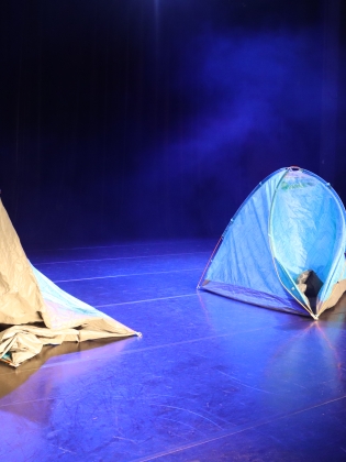 Tre tält på en scen i blått ljus.